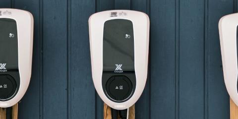 Three EV-Charging stations in a row mounted to a wooden outside wall
