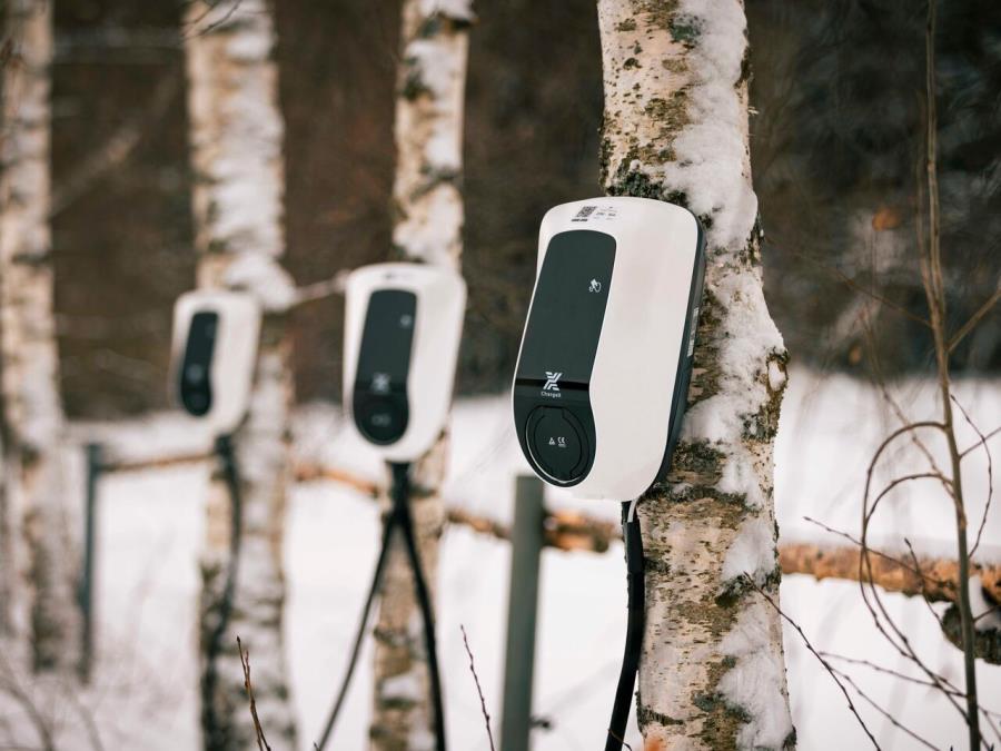 Three charging stations set up in front of trees in the hiking parking lot.