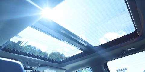 Car interior, looking up through a glass sunroof with sunshine streaming in.