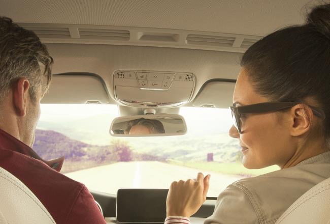 Couple sitting in car driving toward nature