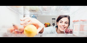A woman reaching for fruit in her refrigerator.