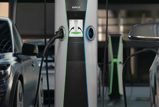 Two electric cars plugged into an electric vehicle charging station