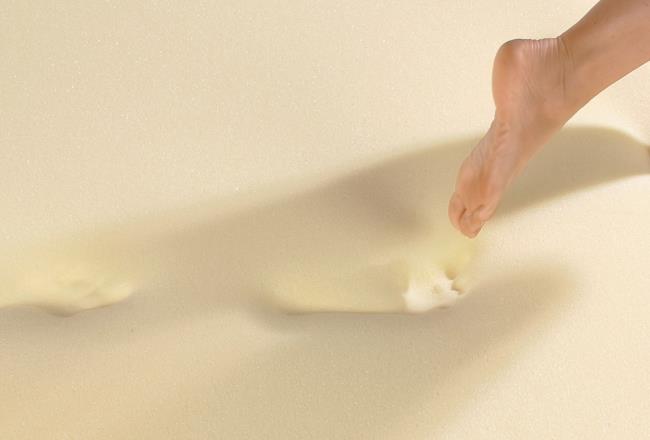 A woman walking on viscoelastic foam that sinks in underneath her footsteps.