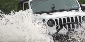 修补后的吉普牧马人在越野驾驶中溅起水花