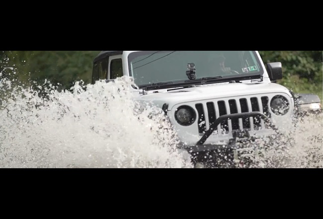 Nachbearbeiteter Jeep Wrangler fährt beim Geländefahren durchs Wasser