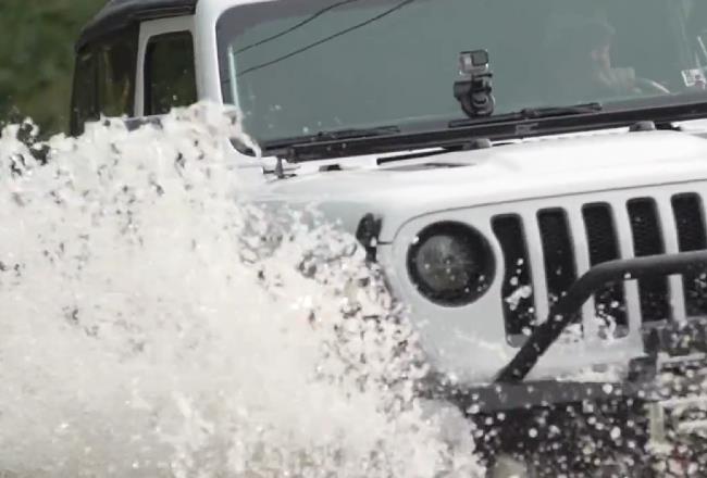 Refinished Jeep Wrangler splashing through water while off-roading