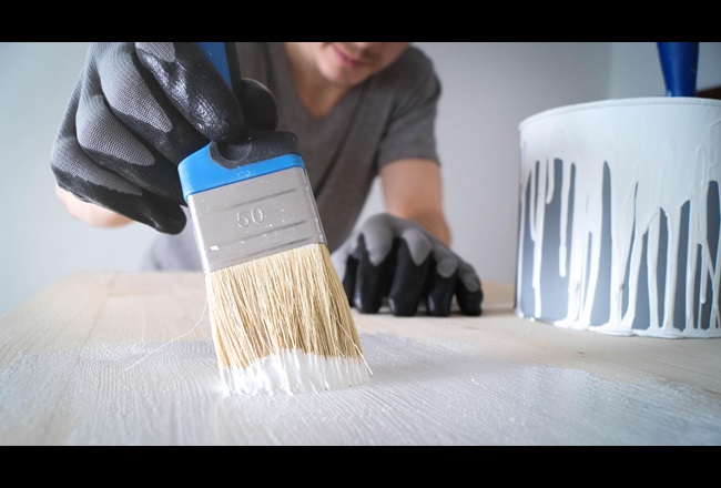 Nahaufnahme: Pinsel mit weißer Farbe auf einem Holztisch und eine Dose mit weißer Farbe