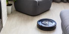 Robot vacuum cleaner navigates a wood floor surface between a fireplace and a sofa