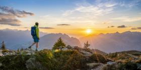 Man walking in front of mountains during sunset