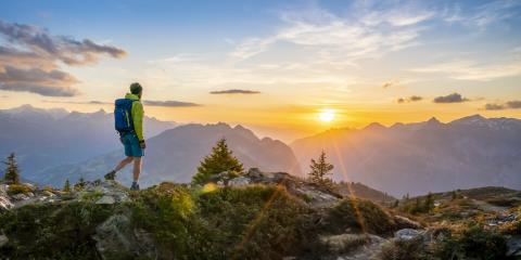 Ein Mann wandert bei Sonnenuntergang vor einem Bergpanorama
