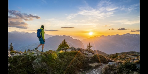 日落时分在山脉前行走的人