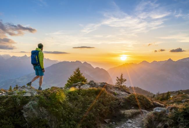 Man walking in front of mountains during sunset