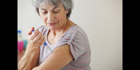 A woman injecting medicine to her upper arm.