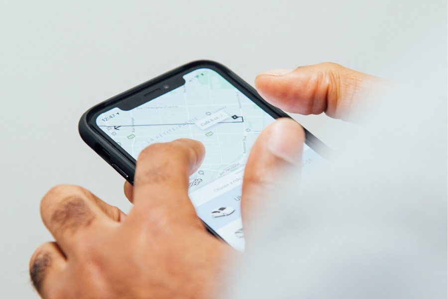 Man holding phone with an open ridesharing app on the screen