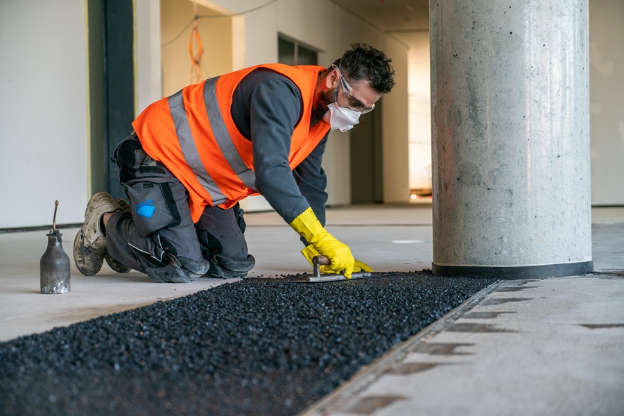 A craftsmen applying dark granulate on the floor.