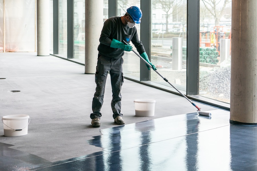 A craftsman seals the freshly-applied flooring material.