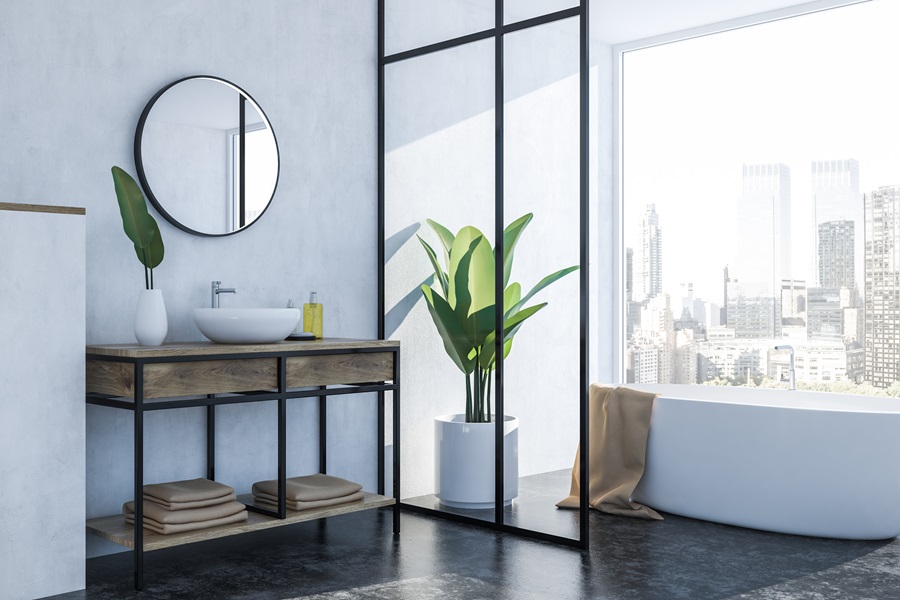 Luxury bathroom corner with white walls, black floor and white sink with round mirror next to white bathtub. 3D rendering.
