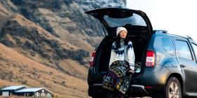 Woman leaning on the load area of an SUV with the rear hatch up.