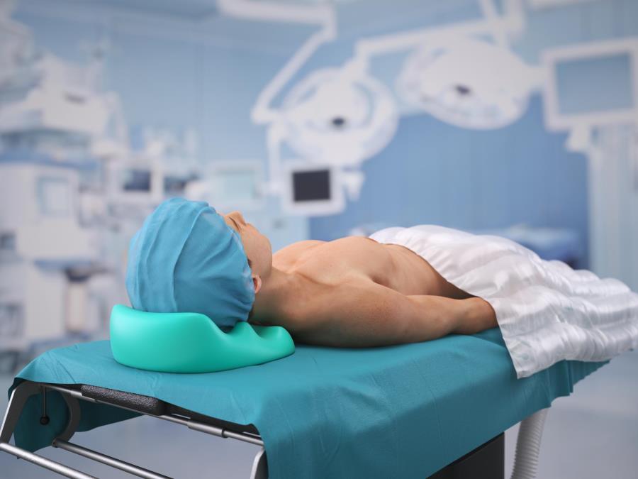 Patient in OR lying on operation table, covered with warming blanket