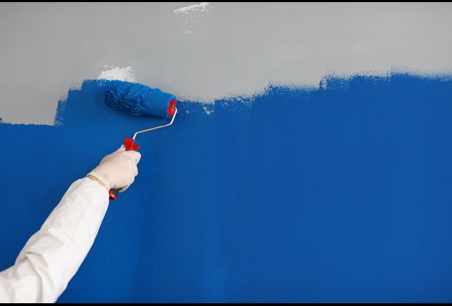 Nahaufnahme eines Erwachsenen, der eine Wand mit leuchtend blauer Farbe anstreicht. Hand mit Farbroller.